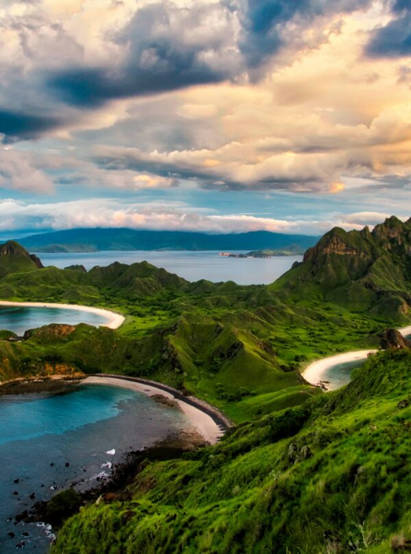 green and brown mountains near body of water under white clouds and blue sky during daytime