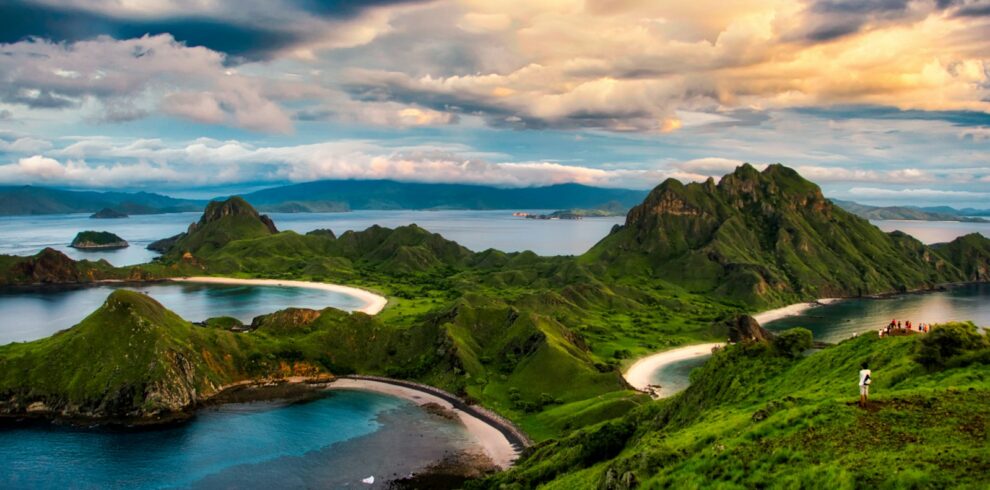 green and brown mountains near body of water under white clouds and blue sky during daytime