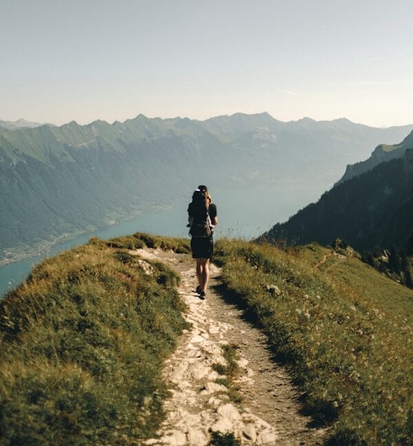 person hiking above mountain overlooking river