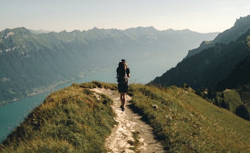 person hiking above mountain overlooking river